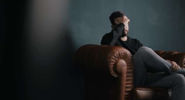 man sitting on couch with head in his hands