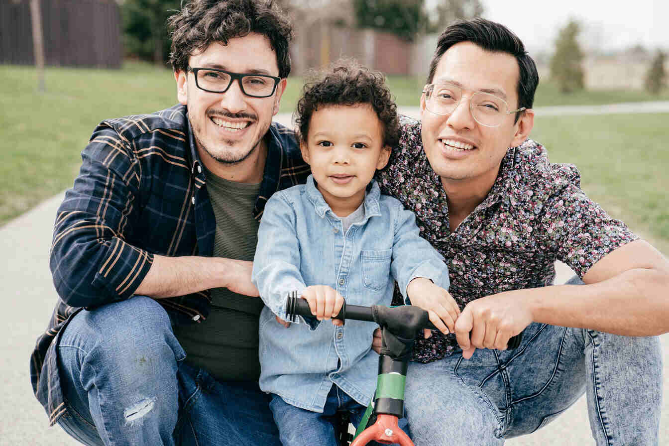 Two men kneeling to take a photo with a toddler.