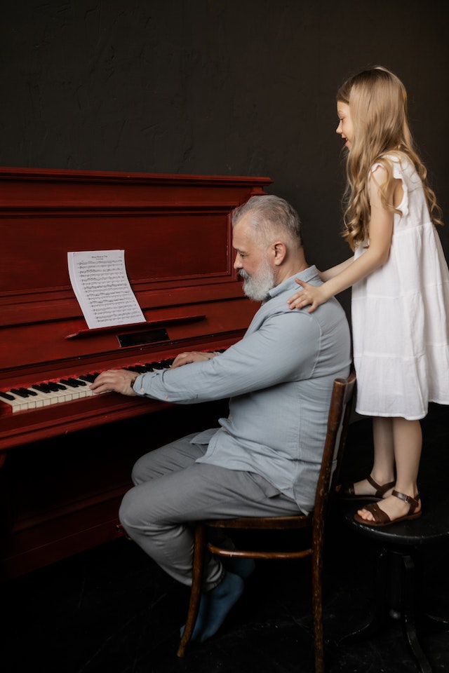 A child watching her grandfather play a piano.