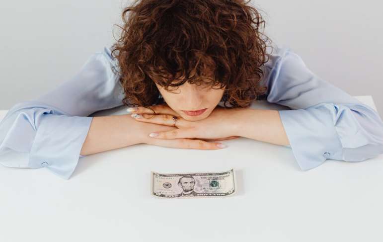 A woman looking at a five dollar bill.