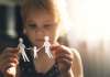 A little girl looking at a paper family in her hands.