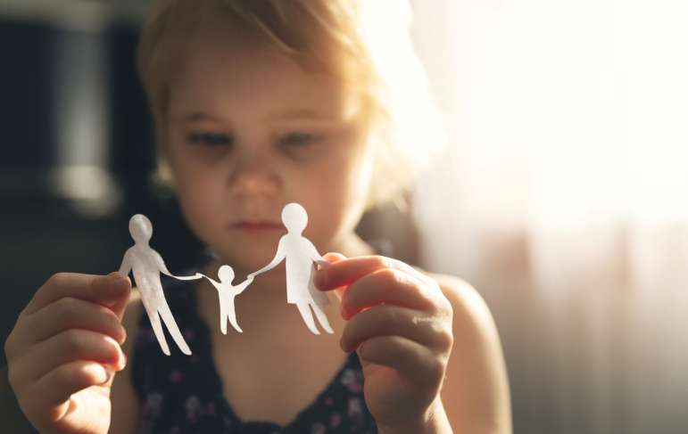 A little girl looking at a paper family in her hands.